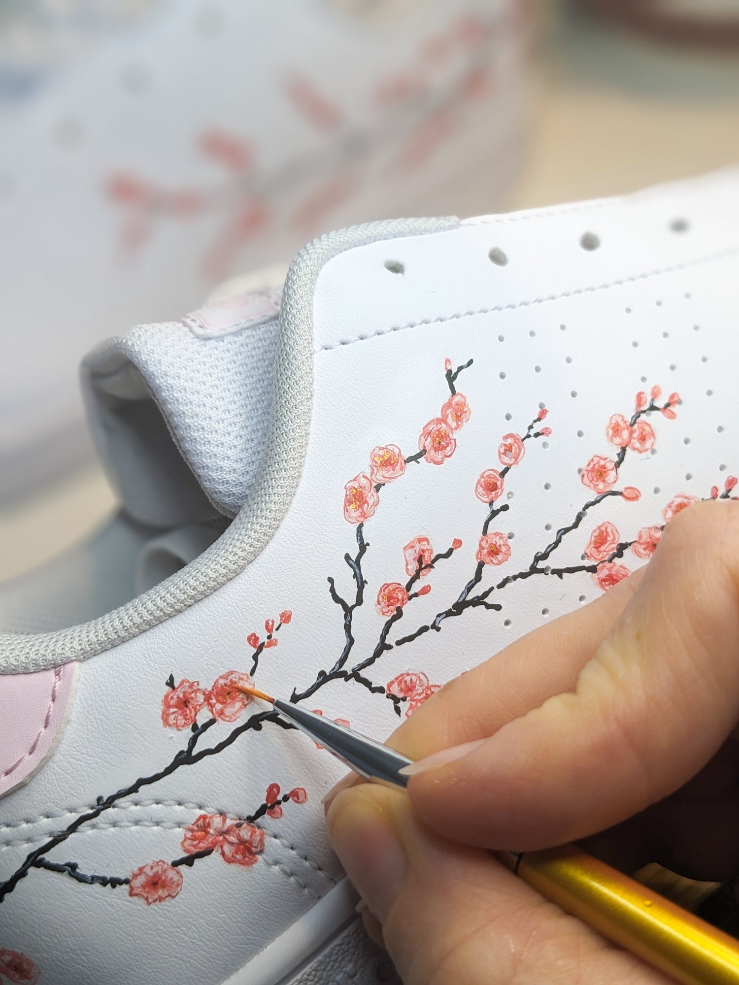 Photo d'une basket en train d'être peinte à la main avec un motif de fleurs de cerisier